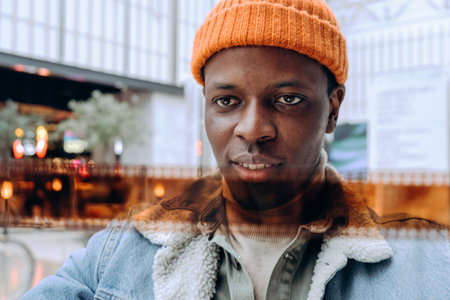 Portrait of confident young man wearing orange beanie in urban settingの写真素材