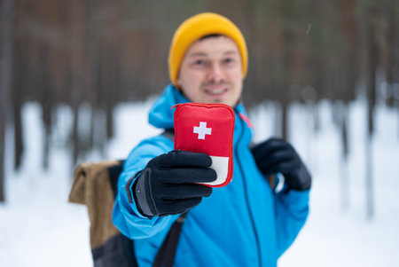 Hiker showing first aid kit in snowy forest during winter tripの写真素材