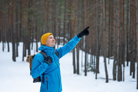 Hiker pointing at something while exploring snowy forest trailの写真素材