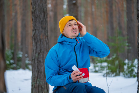 Hiker feeling sick and taking medicine in winter forestの写真素材