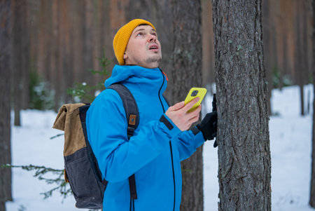 Hiker using smartphone gps app exploring winter forestの写真素材