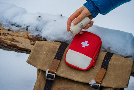 Hiker taking bandage from first aid kit in snowy landscapeの写真素材