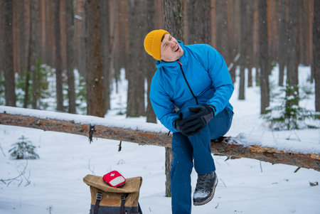 Hiker suffering knee pain in snowy forest during winter tripの写真素材