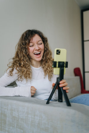 Influencer recording funny video blog using smartphone and tripod at homeの写真素材