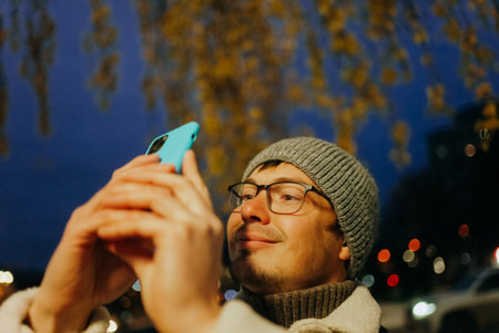 Blogger taking photo with smartphone in autumn evening cityの写真素材
