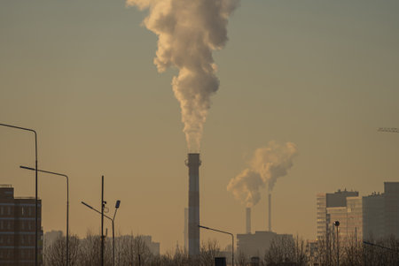 Industrial chimneys releasing smoke into the atmosphere at sunsetの写真素材