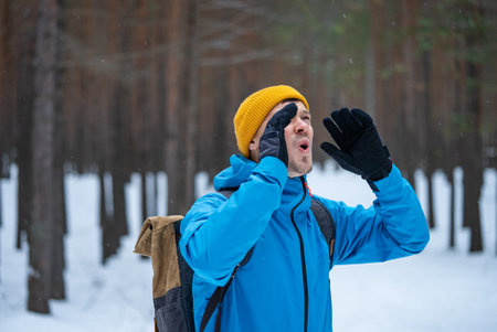 Hiker shouting in snowy forest wearing backpack and winter clothesの写真素材