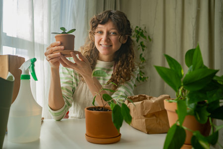 Woman holding potted plant smiling at home gardening hobbyの写真素材