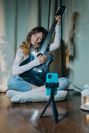 Young musician recording a music performance with acoustic guitarの写真素材