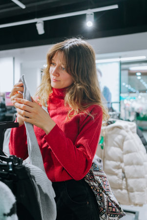 Young woman choosing sweater in clothing storeの写真素材
