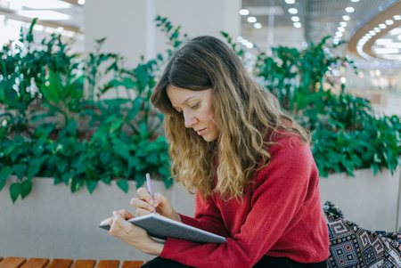Young woman writing in notebook at the mallの写真素材