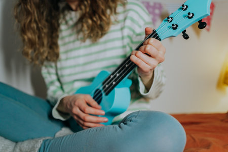 Young woman playing light blue ukulele at homeの写真素材