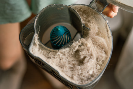 Professional housekeeper emptying dusty container while performing thorough home cleaning, demonstrating effective housekeeping practices for maintaining sanitized living spacesの写真素材