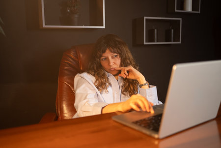 Businesswoman working on laptop in modern office at nightの写真素材