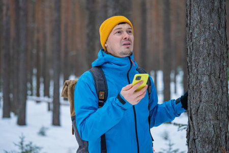 Hiker using smartphone gps app checking location in winter forestの写真素材