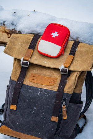 Backpack and first aid kit lying on snow during winter tripの写真素材