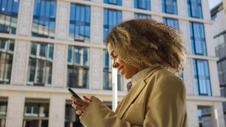 African American woman walks typing messages on phoneの写真素材