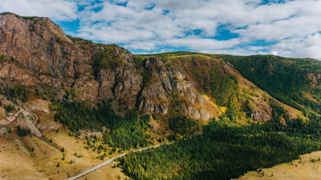 Winding road cutting through lush valley in mountainous landscapeの写真素材