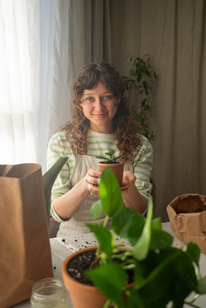 Woman repotting plant at home smiling at cameraの写真素材