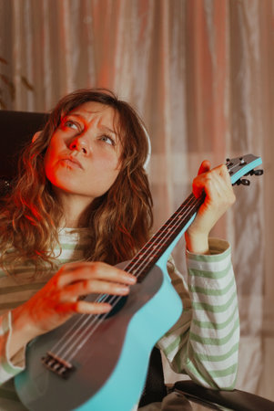 Young woman playing ukulele with red light effectの写真素材