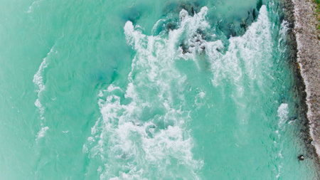 Turquoise river flowing with whitewater rapids and rocky shoreの写真素材