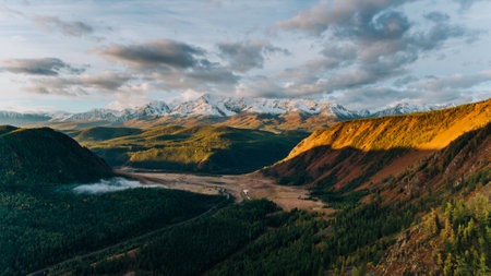 Golden sunlight illuminating autumnal mountains and valley in altai, russiaの写真素材