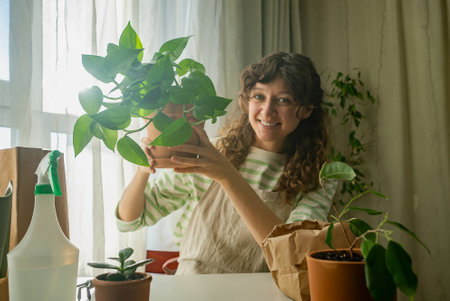 Woman holding potted plant smiling at home gardeningの写真素材
