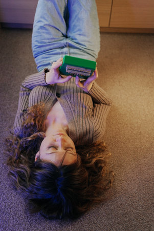 Young woman playing kalimba lying on the floorの写真素材