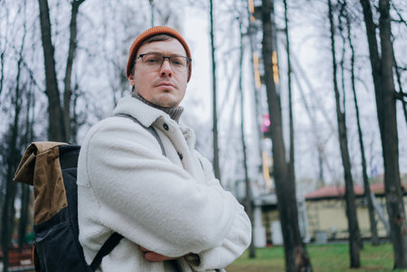 Tourist wearing backpack and warm clothes standing in park with ferris wheel in background