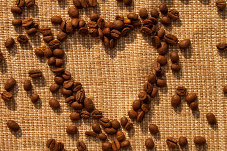 Heart shape coffee beans on a burlap background.の写真素材