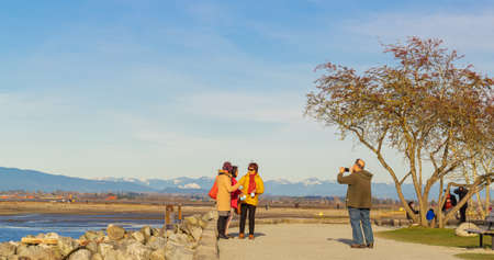 White Rock, BC, Canada-March 8,2021. People at Blackie Spit Park walking and taking pictures by the beautiful seashore. Travel photo, street view, selective focusのeditorial素材