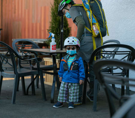 Small asian boy in helmet wearing a face mask and sunglasses with his father in the street buffet. Health care concept. Street view, travel photo, selective focus. April 18,2021 - Guilford, BC, Canada.のeditorial素材