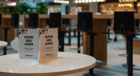 The sign sitting area closed off due to corona virus lockdown measures on the table in the food...