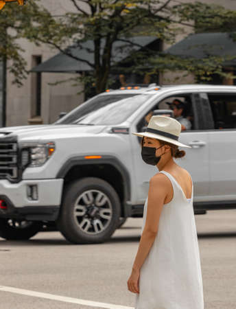 Young Asian woman on a street wearing a protective mask due to protection from Covid-19. Vancouver...
