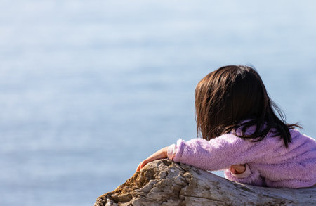A little girl in pink clothes enjoying the view on the beach near sea in sunny day. Street view, travel photo, selective focus, copy space for textの写真素材