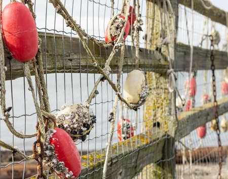 Fishing net with red floats hanging on a fence waiting for better weather. Side view, selective...