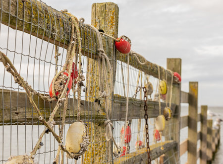 Fishing net with red floats hanging on a fence waiting for better weather. Side view, selective focus, blurred background, nobodyの写真素材