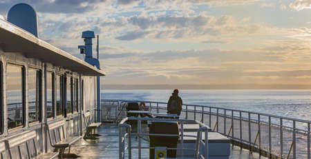 Traveler standing on ferry boat, looking at the sea. Tourist while the boat is sailing. Young woman...