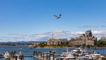 Harbor Air Float-plane flying from Victoria to Vancouver Harbor BC. A Harbor Air Twin Otter plane landing in Victoria Harbor - July 21,2021. Street view, travel photo, selective focusのeditorial素材