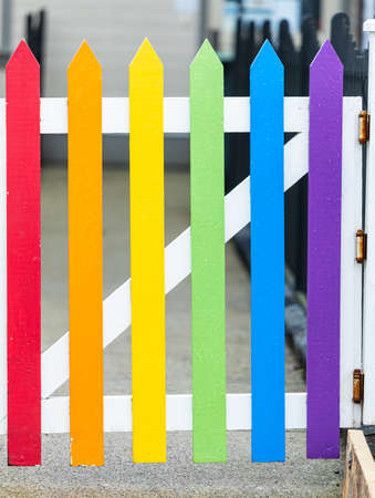 Close-up of a rainbow colored wooden fence gate in a small town. Wooden fence gate painted in rainbow colors. Street photo, travel photo, selective focus.の写真素材