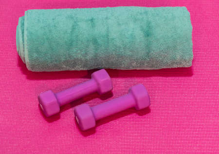Working out, fitness and bodybuilding, healthy and active lifestyle concept with sports towel, pink gym dumbbells on yoga mat floor backgroundの写真素材