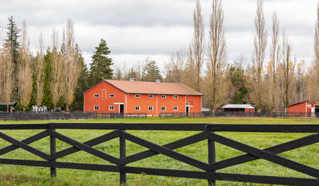 Red barn with fence in countryside during autumn season. Street view, nobody, selective focusの写真素材