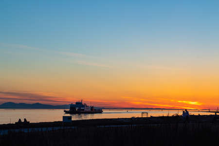 Ship in the sea passing shore near Richmond BC at sunset time-April 18,2021-Canada. Street view, copy space for text, selective focus, travel photoのeditorial素材