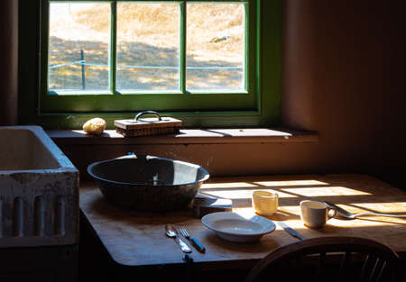 Old times farmhouse interior in a kitchen. Rustic Farmhouse Kitchen. Rural home kitchen with worn wooden table and mixing bowl, spoon, plate. Selective focus, nobody, concept photo old times lifeの写真素材