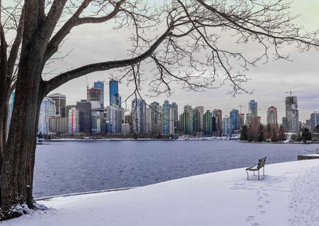 Winter park with snow and view of a downtown of Vancouver BC, Canada in the background during sunset. Street view, selective focus, nobody, travel photoの写真素材