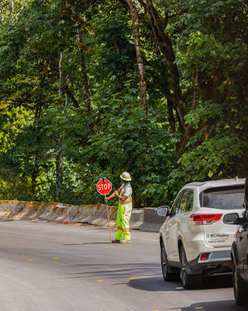A construction worker stopping traffic, holding a stop sign-August 9, 2021-Vancouver Island BC,...