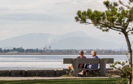 Elderly couple enjoying the afternoon on a calm and peaceful relaxing in front of the ocean view. Copyspace for text, selective focus, travel photoWhite Rock BC, Canada-September 21,2022のeditorial素材