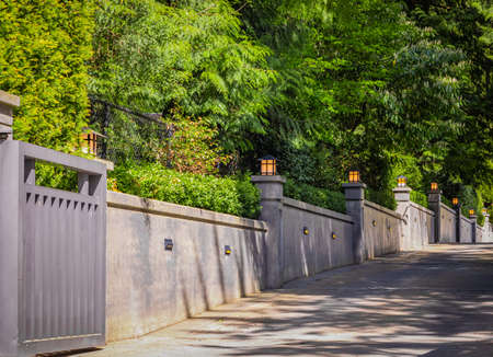 Exterior concrete fence wall with wall lights. Modern concrete fence with night lamps on the pillars. Street photo, nobody, selective focusの写真素材
