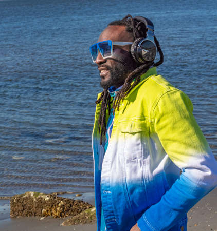 Handsome attractive young african american man with dreadlocks listening music outdoor. street photo. White Rock BC, Canada-March 3,2022のeditorial素材