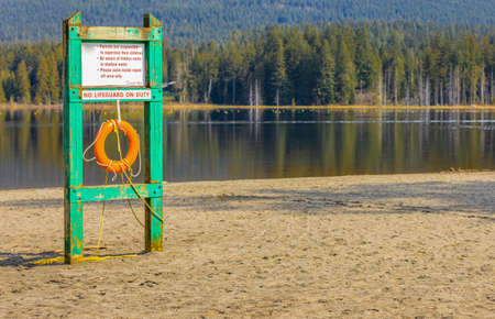 Safety equipment, lifebuoy or rescue buoy hanging on the board. Red lifebuoy on a wooden surface by the lake. Travel photo, nobody, selective focusの写真素材